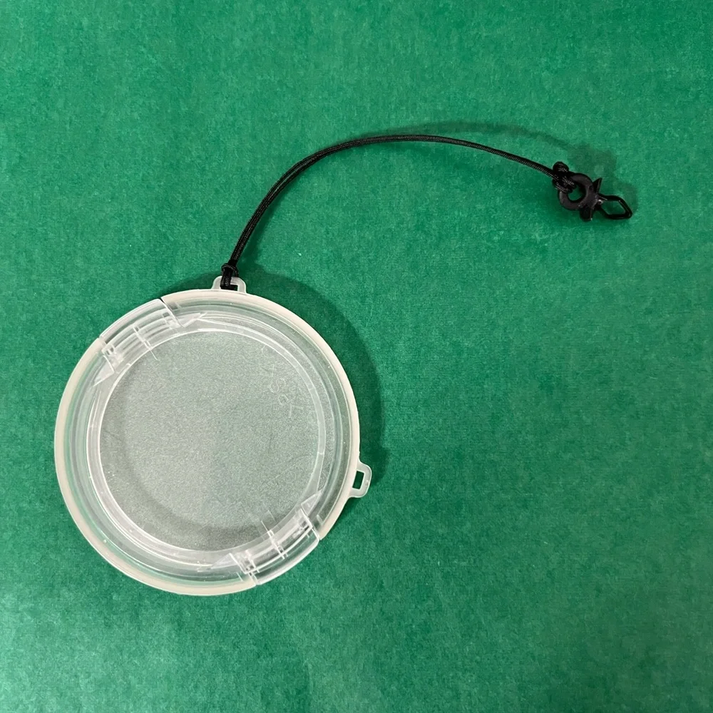 Plastic camera lens cover with string attachment